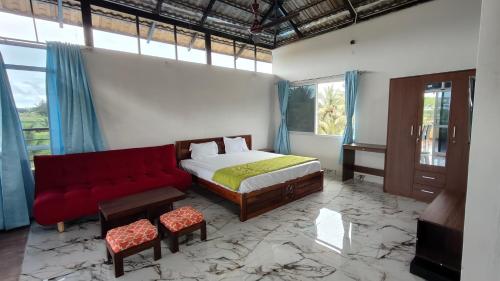 a bedroom with a bed and a red couch at Encanto Farmstay Resort in Mysore