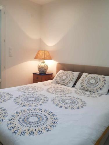 - une chambre dotée d'un lit blanc avec des oreillers et une lampe dans l'établissement Logement indépendant à Fréjus, à Fréjus