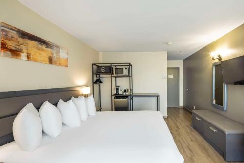 a bedroom with a large bed with white pillows at Les Suites de Laviolette, an Ascend Collection Hotel in Trois-Rivières