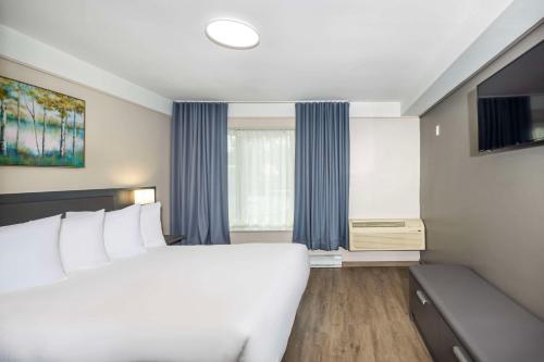 a bedroom with a large white bed and a window at Les Suites de Laviolette, an Ascend Collection Hotel in Trois-Rivières