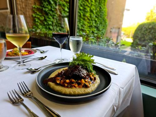 a plate of food on a table with wine glasses at Hotel Le Victorin, an Ascend Hotel Collection Member in Victoriaville