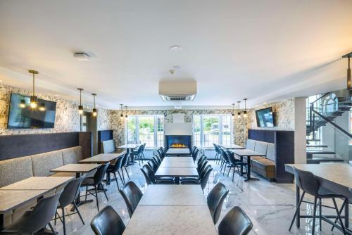 a restaurant with tables and chairs and a fireplace at Les Suites de Laviolette, an Ascend Collection Hotel in Trois-Rivières