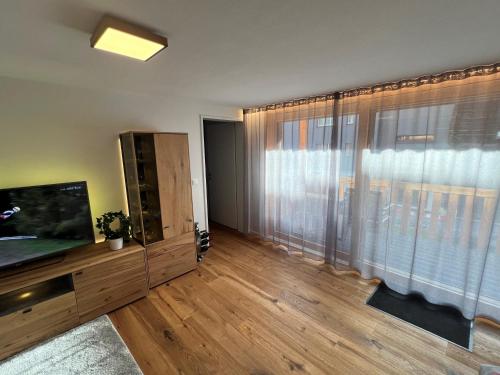 a living room with a television and a large window at Larix in Ulrichen