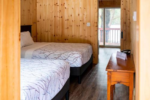 a bedroom with two beds and a wooden wall at The Grand Tappattoo Resort, an Ascend Collection Resort in Seguin 