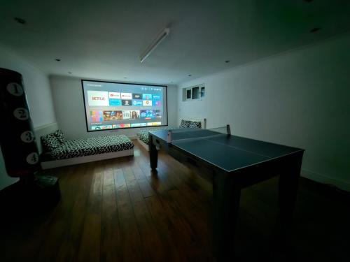 a room with a ping pong table and a large screen at Annexe pool table air hockey table tennis movie in Windsor