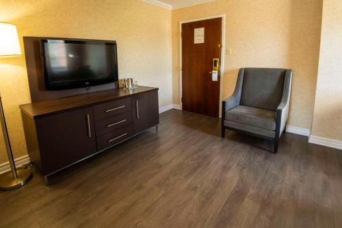 a hotel room with a television and a chair at Chateau Cartier Hotel & Resort, an Ascend Collection Resort in Gatineau