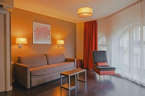 a living room with a couch and a chair at Comfort Aparthotel Saint-Etienne in Saint-Étienne