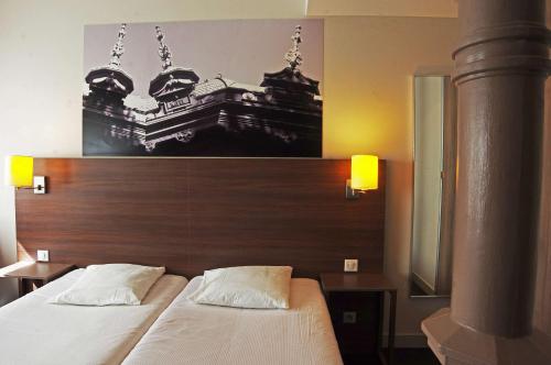 a bedroom with a bed with a wooden head board at Comfort Aparthotel Saint-Etienne in Saint-Étienne