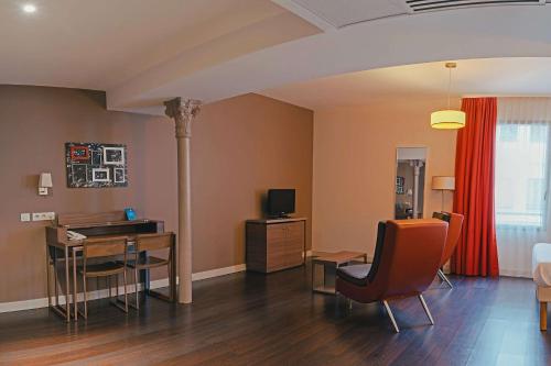 a living room with a desk and a table with chairs at Comfort Aparthotel Saint-Etienne in Saint-Étienne