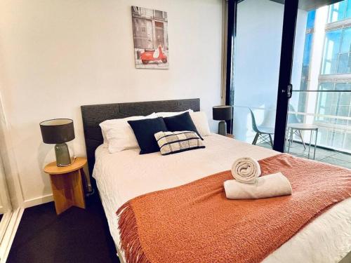 a bedroom with a large bed with an orange blanket at Stunning Stay Steps away from Crown with Free Parking in Melbourne