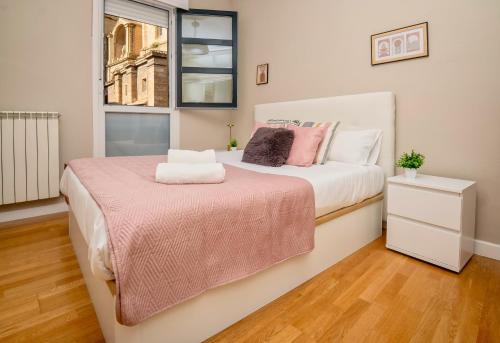 a bedroom with a bed with a pink blanket and a window at Santiago Tower Aire Ac casco antiguo By Apartamentos Logrono in Logroño