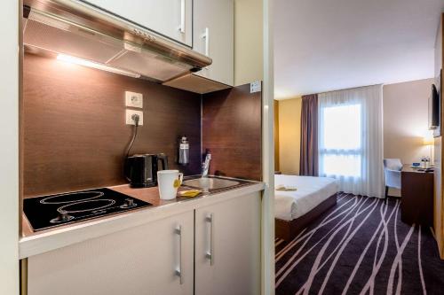 a kitchen with a sink and a bed in a room at Comfort Aparthotel Bordeaux Begles Arena in Bègles