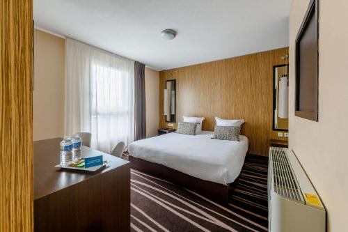 a hotel room with a bed and a desk with a television at Comfort Aparthotel Bordeaux Begles Arena in Bègles