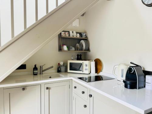 a kitchen with white cabinets and a counter top with a microwave at Fabulous Barn in Great Wolford Moreton in Marsh in Shipston on Stour