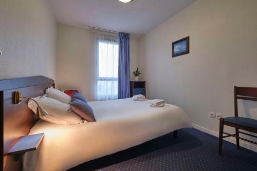 a hotel room with a large bed with pillows at Comfort Aparthotel Carcassonne in Carcassonne