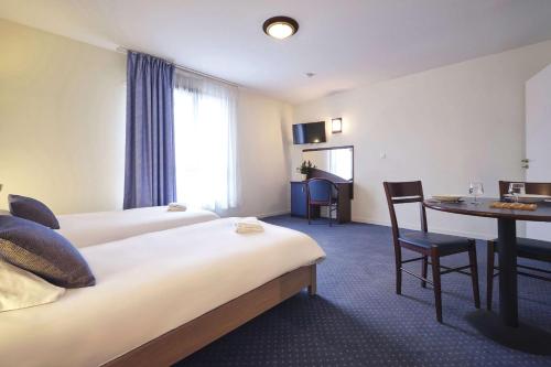 a hotel room with two beds and a table at Comfort Aparthotel Carcassonne in Carcassonne