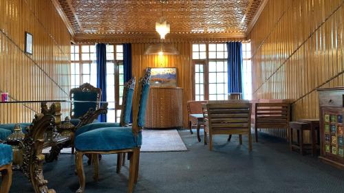 a room with chairs and a table and windows at Serene by Juniper Resorts in Srinagar
