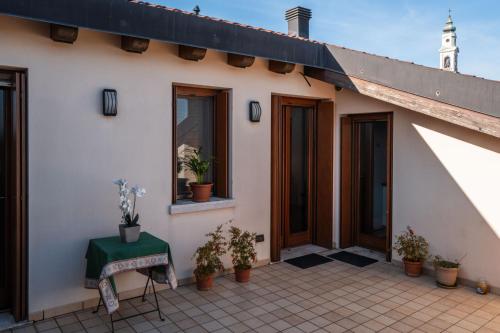 a white house with a green table and potted plants at Alba dei Grappoli in Spresiano