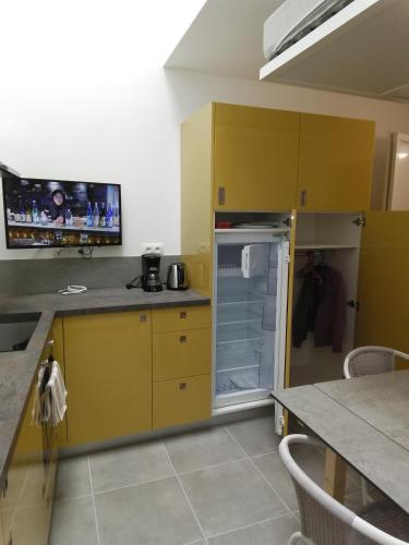 La cuisine est équipée de placards jaunes et d'un réfrigérateur ouvert. dans l'établissement La Rabouillère, à Cormaranche-en-Bugey