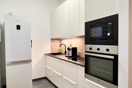 a white kitchen with a microwave and a stove at Lang's square apartment in Zagreb