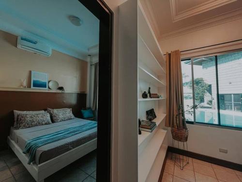 a bedroom with a bed and a large window at Casa Vista by Hooga Home Bungalow Guest House in Talisay