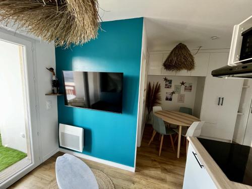 a kitchen with a blue wall and a table at Charmant appartement in Lacanau