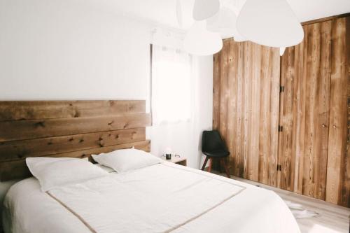 une chambre avec un lit blanc avec une tête de lit en bois dans l'établissement Le Repaire 830 - Appartement 6 personnes - Saint Lary Soulan, à Saint-Lary-Soulan