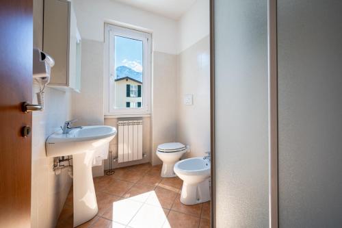 a bathroom with a sink and a toilet and a window at My Holidays New Eden in Domaso
