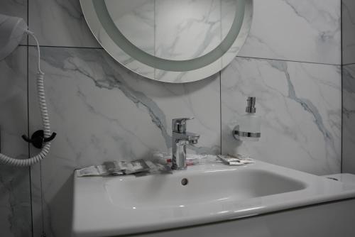 a white sink in a bathroom with a mirror at West Hotel in Mostiska