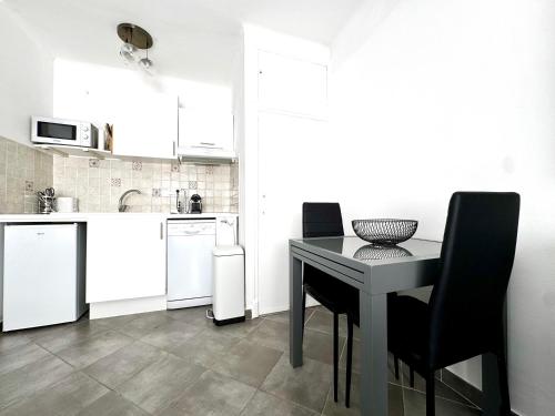 une cuisine avec une table noire et des chaises noires dans l'établissement Studio vue mer terrasse à 1min des plages, à Juan-les-Pins