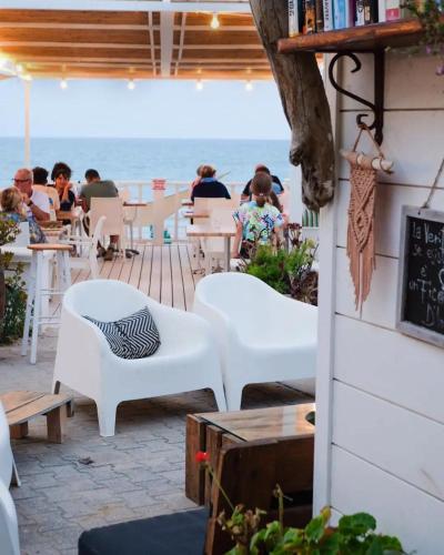 a patio with people sitting at tables and the ocean at Villaggio Porticello Mare in Vieste