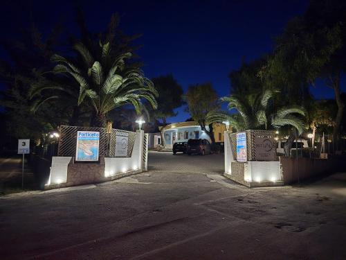 a parking lot with a fence and palm trees at night at Villaggio Porticello Mare in Vieste