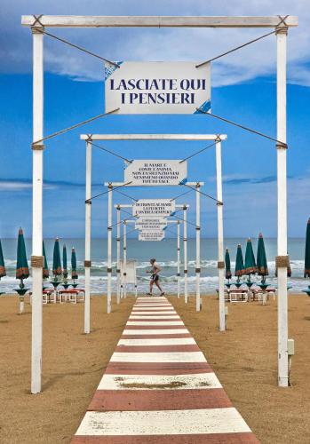 a walkway on the beach with chairs and umbrellas at Villaggio Porticello Mare in Vieste