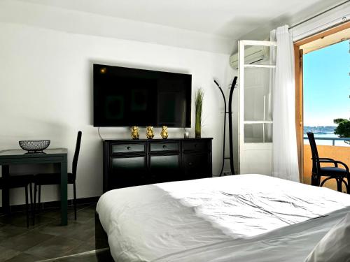 une chambre avec un lit et une télévision sur un mur dans l'établissement Studio vue mer terrasse à 1min des plages, à Juan-les-Pins