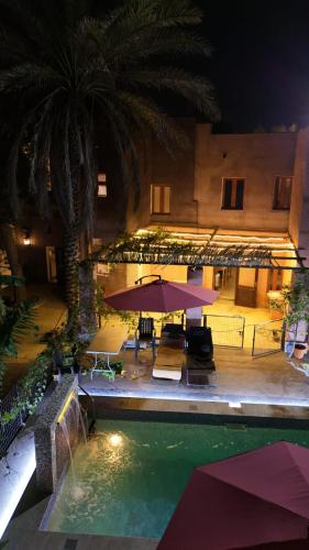 an outdoor swimming pool with a table and umbrella at Riad Nizwa in Nizwa