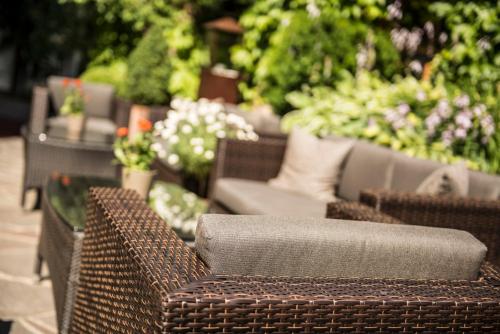 a group of wicker chairs in a garden at Hotel Angelo Engel in Ortisei