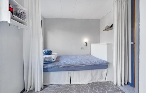 a small room with a bed with curtains in it at 2 Bedroom Amazing Home In Væggerløse in Marielyst