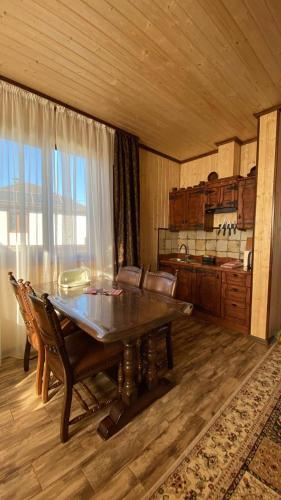 a dining room with a wooden table and a large window at Five House in Skhidnitsa