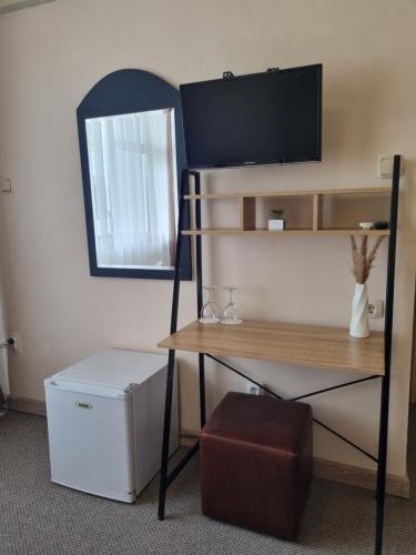 a room with a desk with a television on a wall at Dezudava Family Hotel in Sandanski