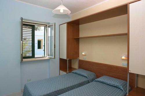 a room with two beds and a mirror and a window at Villaggio Porticello Mare in Vieste