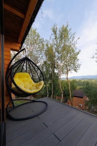 a wicker chair sitting on the deck of a house at Vdoma Karpaty in Vilshynki