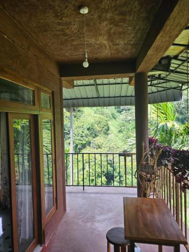 a porch with a wooden table and a balcony at Creek Downhills in Ella