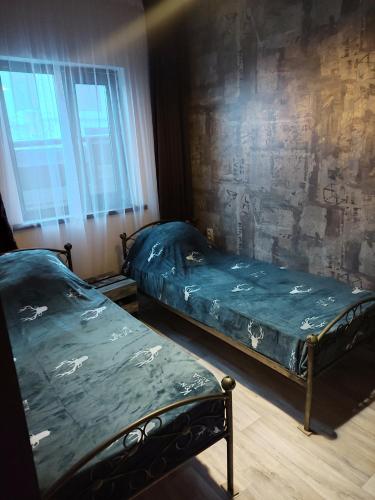 two twin beds in a room with a wall at Sky loft house in Almaty