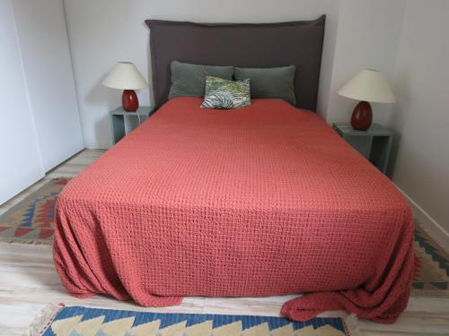 a bedroom with a red bed with two lamps at T3 cadre champêtre Saint Jean de Luz in Saint-Pée-sur-Nivelle