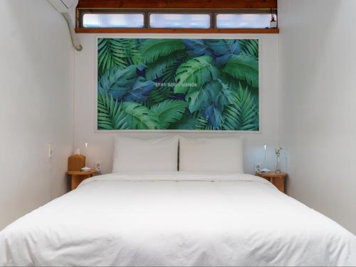 a bedroom with a white bed and a painting on the wall at Exclusive House Hanok Stay 'Soo Hanok' in Suncheon