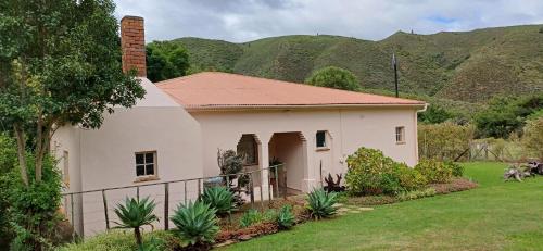 a small white house with mountains in the background at Assegai Rest in Robertson