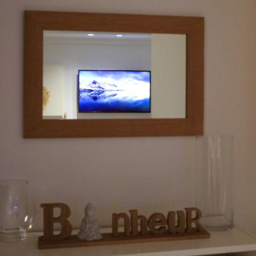 a mirror on a wall with a tv on a shelf at Blue Hideaway in Saint Barthelemy