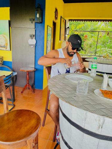 a man sitting at a table drinking from a glass at Blue Pillars Kandy in Kandy