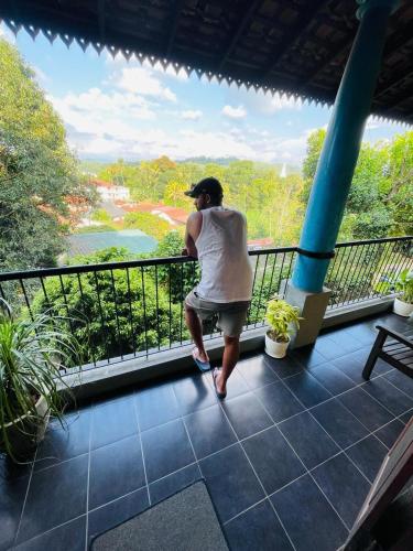 a person standing on a balcony looking at a river at Blue Pillars Kandy in Kandy