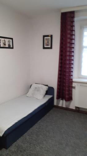 a bedroom with a bed with a red curtain and a window at Apartament LORD in Toruń